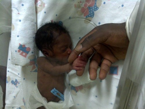 Nimmy holding mum's finger in an incubator